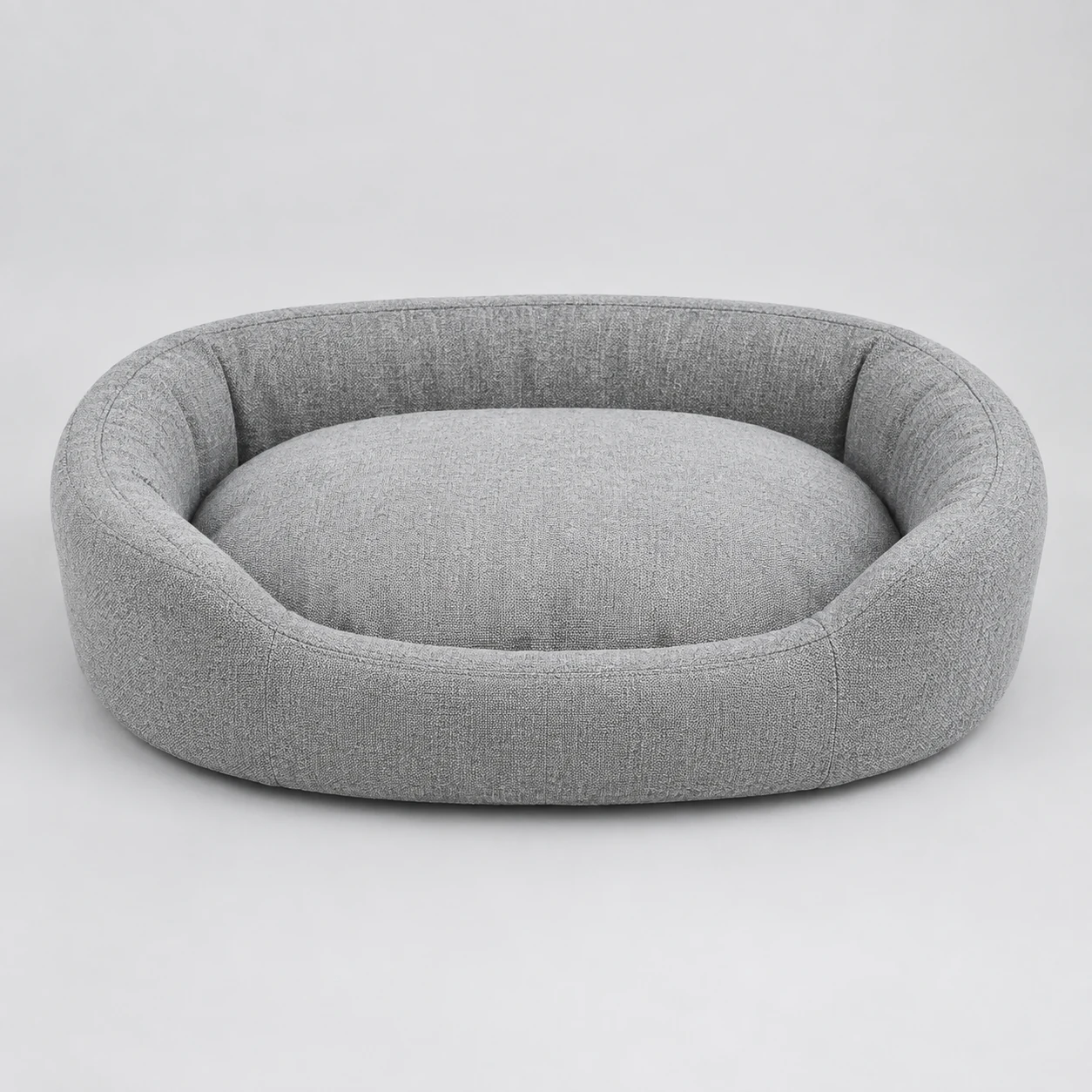 Oval bolster pet bed with padded rim on a neutral background